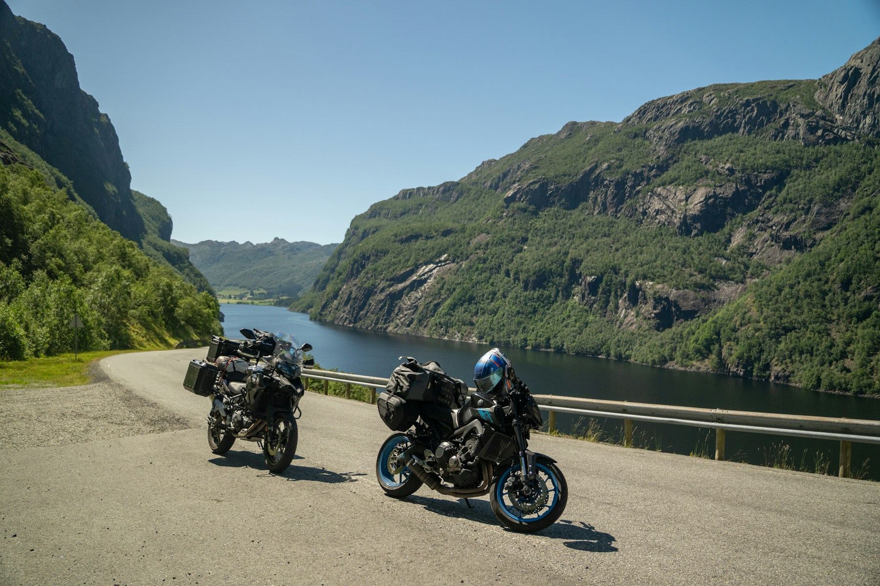Two touring motorcycles on a waterside road in Rogaland, Norway
